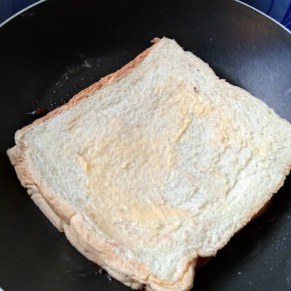 Tutup dengan roti tawar lagi. Olesi bagian atas roti dengan margarin.