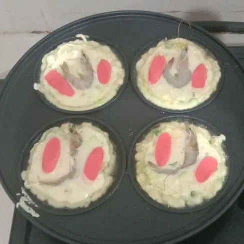 Siapkan cetakan. Masukkan adonan ke dalam cetakan. Kemudian beri sosis dan udang di atas adonan. Tunggu setengah matang.