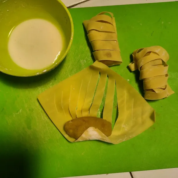 Ambil kulit lumpia, potong searah diagonal, mekarkan dengan menarik kedua ujung kulit ke arah berlawanan. Taruh ubi di bagian pinggir dan gulungan. Lem bagian luar kulit lumpia dengan tapioka yang sudah ditambah air.