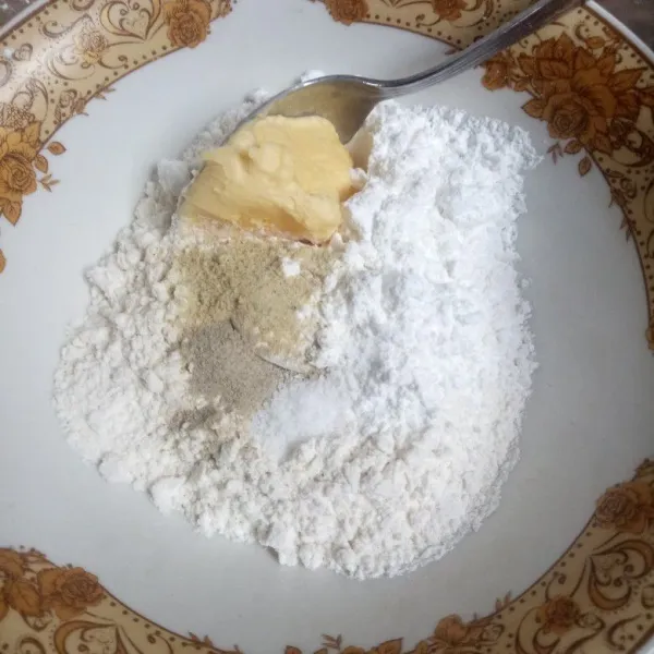 Masukkan tepung terigu dalam mangkuk, tambahkan tepung maizena, garam halus, bawang putih bubuk, merica bubuk, kaldu bubuk dan margarin.
