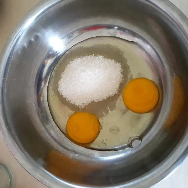Sipakan wadah lain, masukan telur dan gula, lalu aduk sampai gula larut.