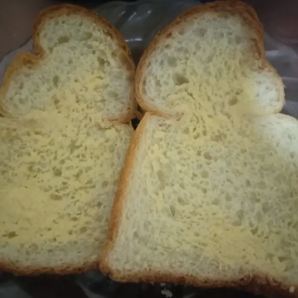 Oles roti dengan margarin.