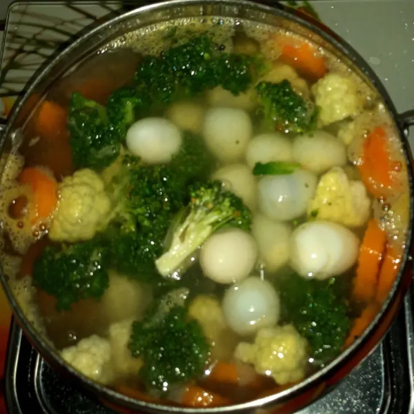 Masukkan borokoli, kembang kol dan tekur puyuh, masak sampai semua sayuran cukup matang. Koreksi rasa.