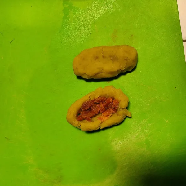 Ambil ubi halus 1 sdm, pipihkan, lubangi tengahnya dan isi dengan gula merah sisir. Tutup kembali ubi.