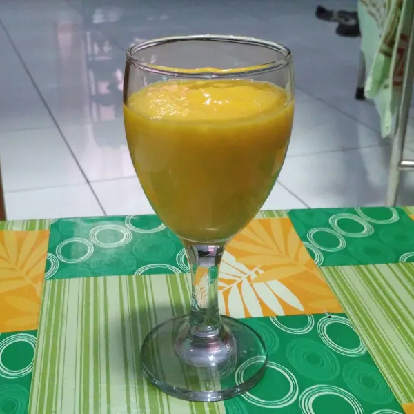 Tuang jus mangga dalam gelas.
