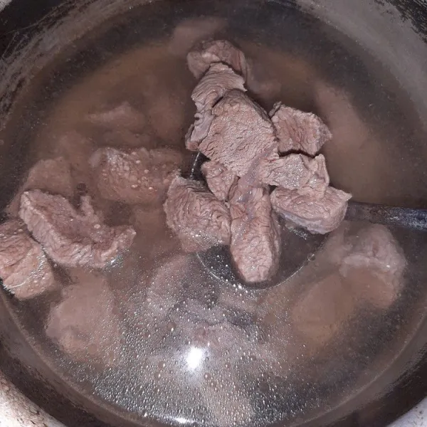 Rebus daging yang telah dipotong-potong, setelah mendidih ganti air rebusannya supaya jernih.