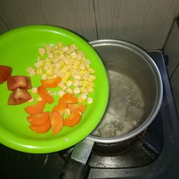 Masukan jagung,wortel dan tomat ke panci kuah ayam.Rebus dengan api sedang sampai setengah matang.