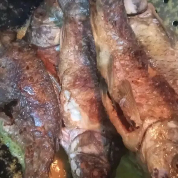 Masukkan ikan mas goreng. Bolak balik ikan dan tutupi dengan bumbu.