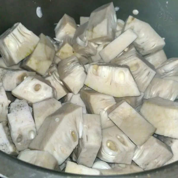 Kupas nangka dan potong-potong, rebus hingga setengah matang lalu buang airnya.