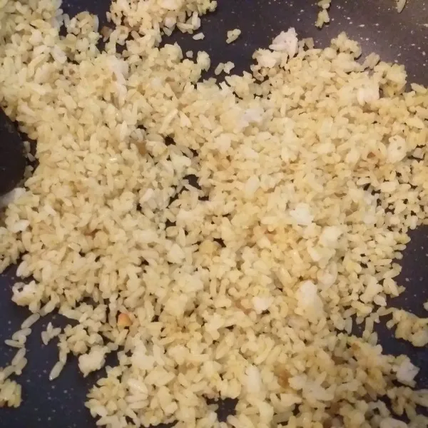 Masukkan nasi putih dan aduk rata. Masukkan sedikit garam, kaldu jamur dan lada bubuk. Aduk rata kembali.