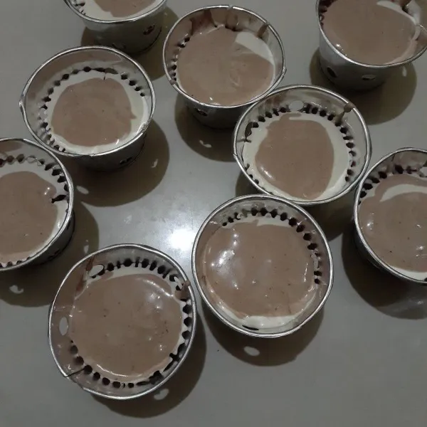 Siapkan cetakannya, alasi cetakan dengan papercup. Tuang adonan putihnya, lanjut tuang adonan coklatnya dgn cara selang seling penuangannya atau sesuai selera.