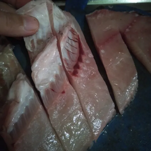 Potong memanjang fillet ikan nila. Cuci bersih.