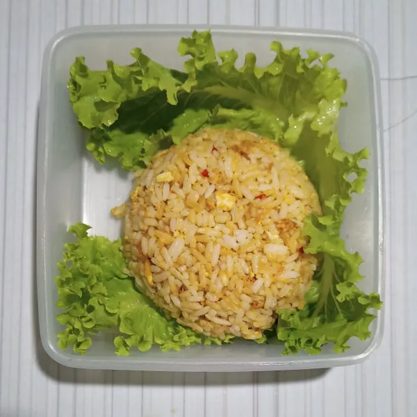 Tangkupkan cetakan nasi goreng ke atas daun selada.