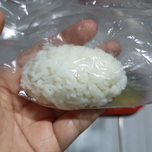 Siapkan nasi putih lalu kepal2kan dengan dilapisi plastik bersih membentuk bulat lonjong.