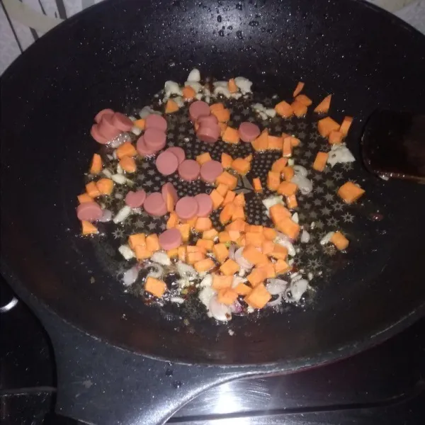 Panaskan teflon lelehkan mentega , tumis bawang putih cincang ,masukan sosis dan wortel diaduka rata masak sampai layu.