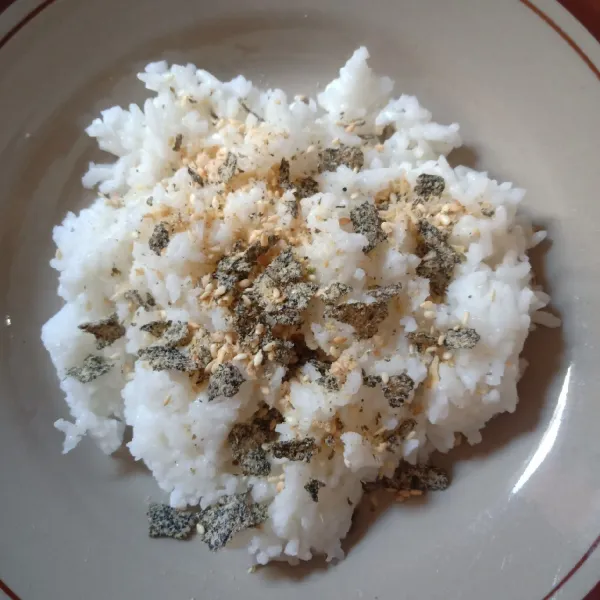 Ambil 1 centong nasi yang masih panas. Biarkan sampai hangat lalu taburi furikake. Aduk rata.