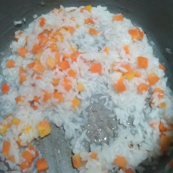 Sebelum membuat nasi tim bayi Anda. Pertama, cuci bersih beras tambahkan air masak hingga air menyusut, matikan api, tambahkan potongan wortel aduk rata.