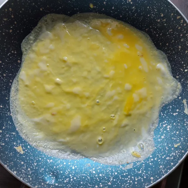 Panaskan teflon lalu tuang telur sedikit dan ratakan sampai membentuk lingkaran.