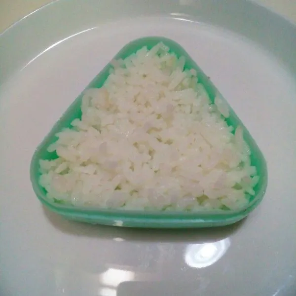 Basahi cetakan onigiri, taburi secukupnya wijen sangrai, lalu isi dengan nasi hingga 1/3 bagian, tekan².