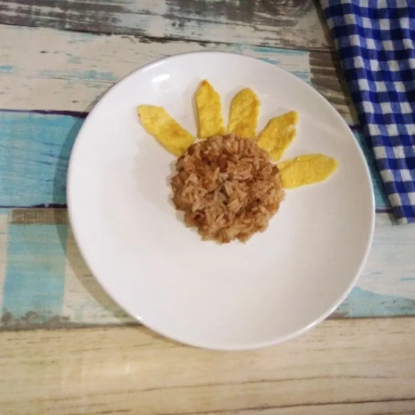 Kemudian ambil potongan Telur yang telah dibentuk, taruh mengelilingi bundaran nasi goreng.