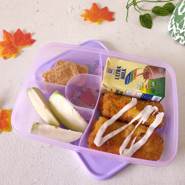 Tata pada lunch box : risoles, susu kemasan, buah dan biskuit. Beri sedikit mayonaise di atasnya.