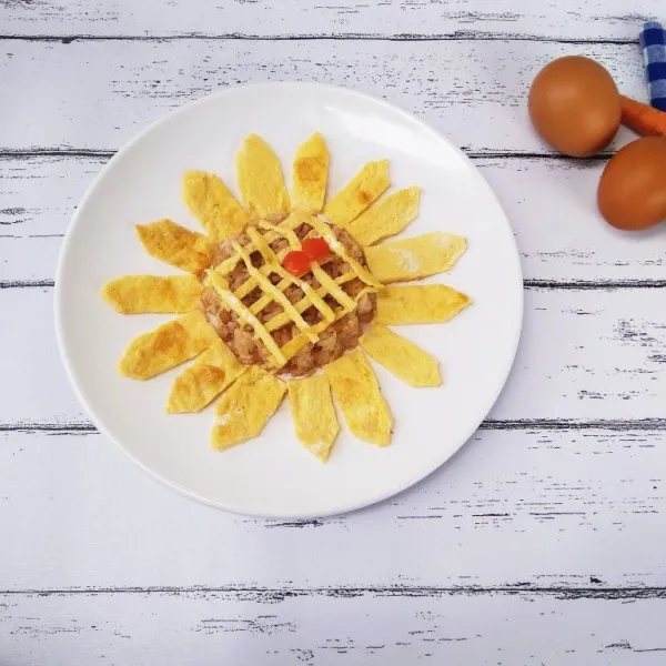 Tambahkan juga Potongan telur bentuk korek api dan tutupi permukaan nasi goreng, hias sedikit biar makin cantik, dan sajikan untuk anak tercinta.