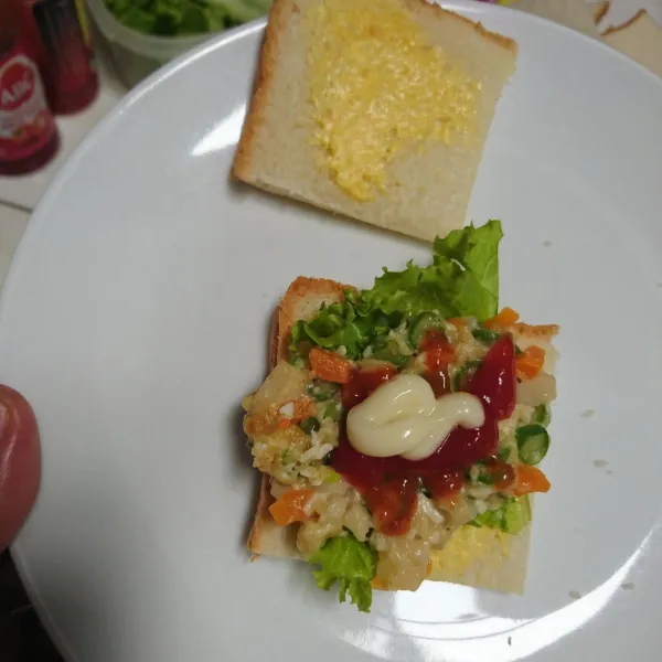 Oleskan roti dengan margarin. Lapisi daun selada. Oleskan isi, saus sambal, saus tomat dan mayonaise. Tutup dengan roti.
