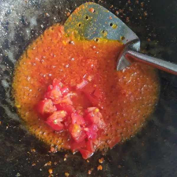 Tumis bumbu halus sampai harum, lalu tambahkan irisan tomat dan aduk rata