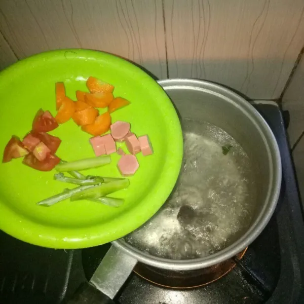 Cuci bersih dan iris wortel,tomat,sosis dan tangkai kailan.Masukan ke panci,masak sampai setengah matang.