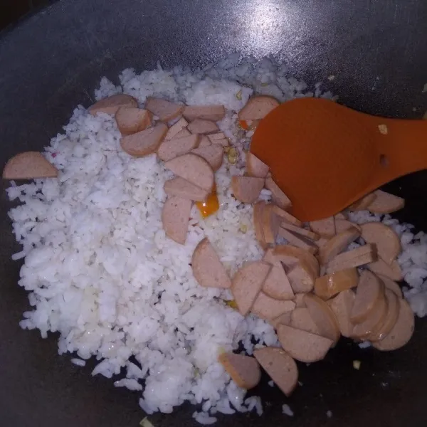 Masukkan nasi putih dan sosis. Aduk kembali hingga tercampur rata.