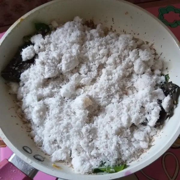 Masukkan kelapa, aduk rata, kemudian kecilkan api.