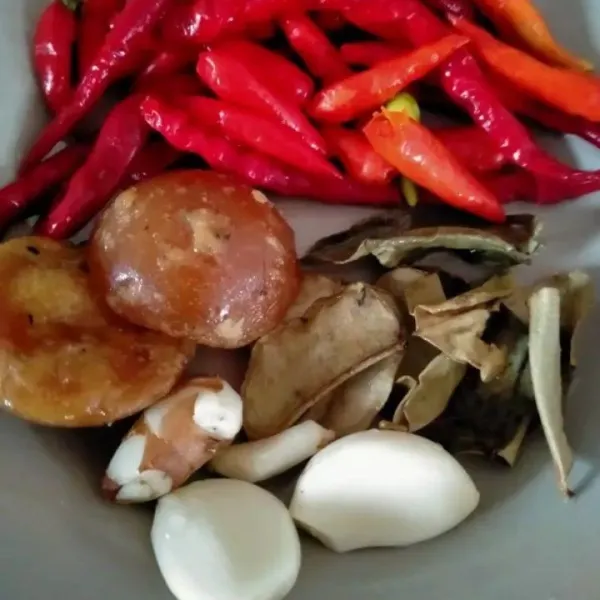Haluskan bawang putih, lombok, gula merah, kencur, dan daun jeruk.