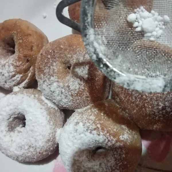 Taburi permukaan donat dengan gula halus. Sajikan.