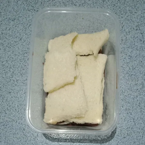 Susun di wadah 1 lembar roti tawar yang dipotong acak sesuai selera.