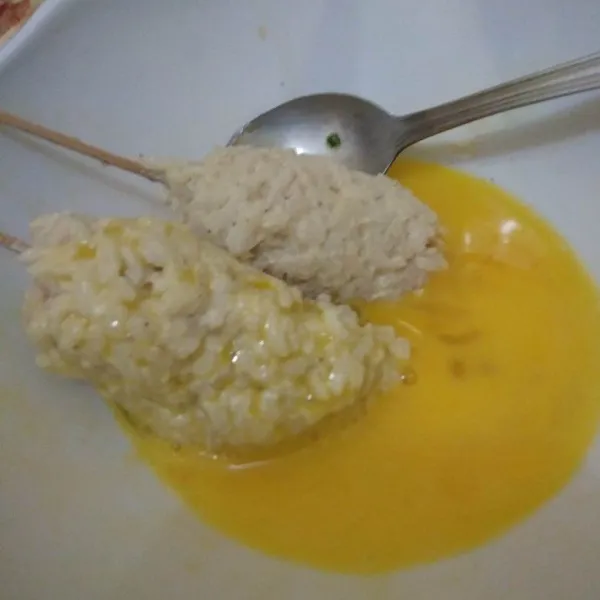 Kocok telur dalam mangkok, celupkan nasi sosis ke dalam kocokan telur.