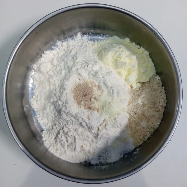 Campur tepung terigu, susu bubuk, gula pasir, ragi instan, kismis dan garam. Aduk rata.