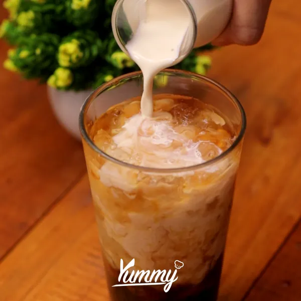 Tuangkan teh hitam hingga ¾ gelas, lalu tuangkan susu evaporasi hingga penuh.
