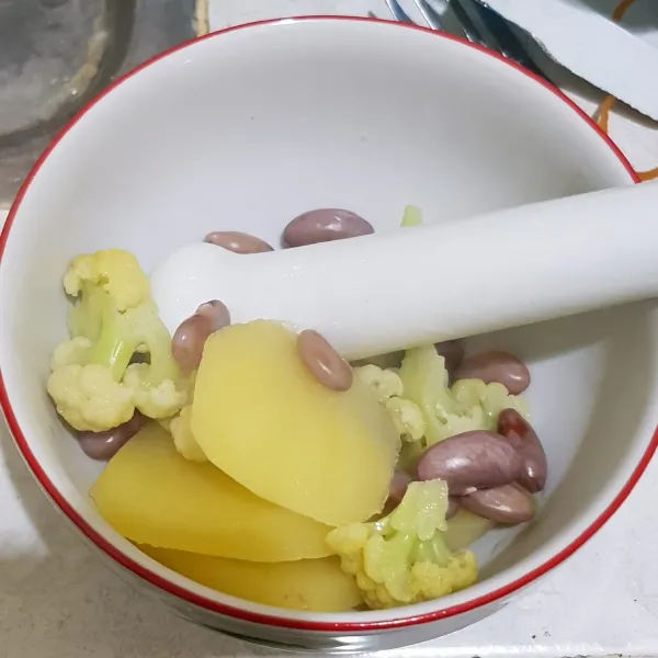 Tumbuk kasar kentang, kacang merah dan kembang kol dalam mangkok.