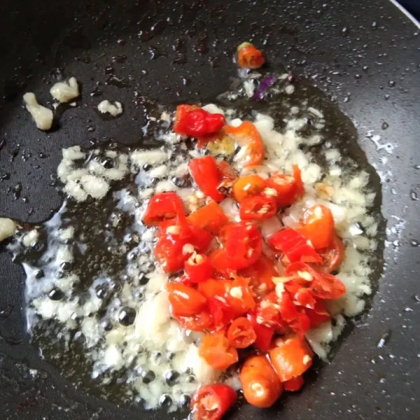 Tumis bawang putih hingga harum, masukan irisan cabe rawit, aduk rata.
