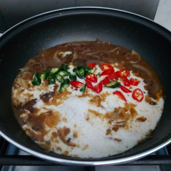 Buka tutup teflon, nyalakan api. Tambahkan santan, cabe merah besar dan cabe hijau besar. Aduk rata dan koreksi rasa.