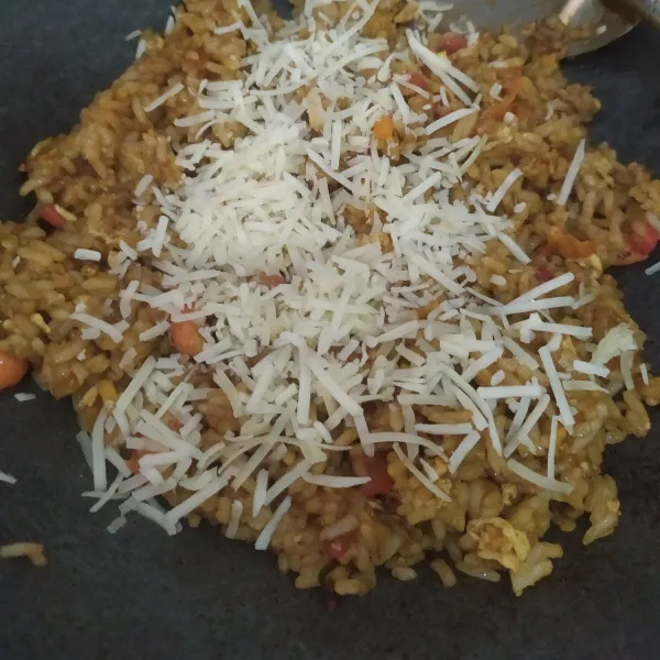 Tambahkan keju, aduk, sesuaikan rasanya, tambahkan garam jika perlu, masak sampai nasi panas merata, angkat dan sajikan bersama timun.