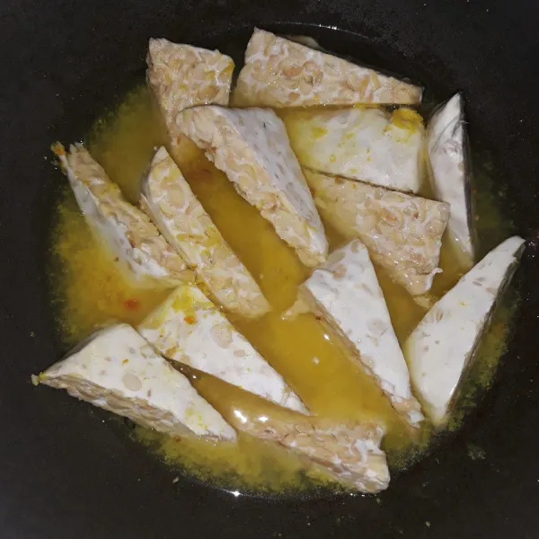 Masukkan tempe dan garam ke dalam bumbu ungkep.