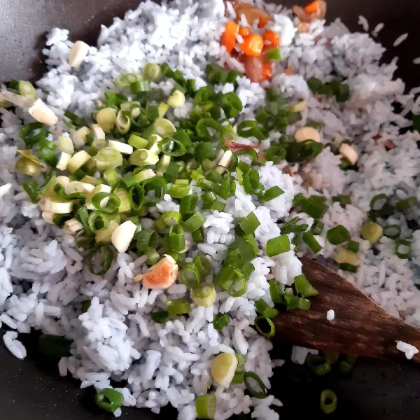 Masukkan nasi dan daun bawang.