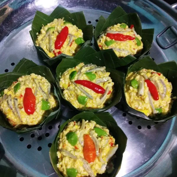 Masukan adonan mangkuk ikan teri tahu ke dalam takir, beri cabai rawit. Panaskan panci kukusan. Kukus selama 25 menit atau sampai matang.