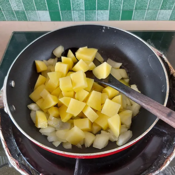 Tumis bawang bombay dengan margarin. Masukkan kentang, aduk-aduk hingga agak layu.