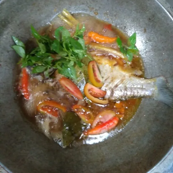 Setelah ikan sudah matang, masukkan tomat, daun kemangi dan cabe rawit.