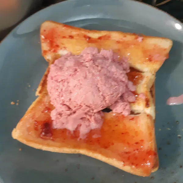 Susun roti di atas piring saji, tambahkan ice cream strawberry di atas roti.