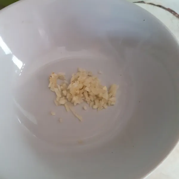 Geprek dan cincang halus bawang putih, letak dalam wadah.