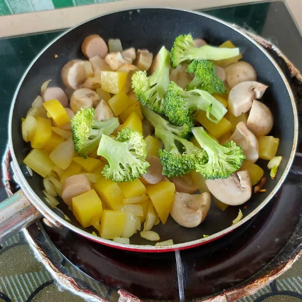 Masukkan jamur dan brokoli, aduk sebentar.