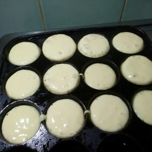 Panaskan cetakan, oles dengan minyak goreng. Tuang adonan hingga 3/4 bagian, jangan terlalu penuh nanti luber. Bisa diberi isian sesuai selera, tanpa isian pun enak. Jika bagian bawah sudah tampak kokoh, balik kue, tunggu sampai matang, angkat, sajikan dengan taburan gula halus.